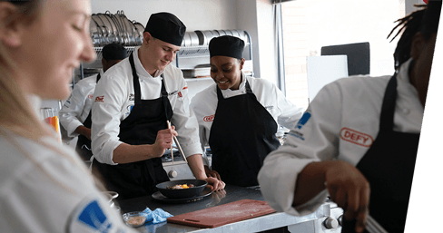 A group of chefs are preparing food in a kitchen.