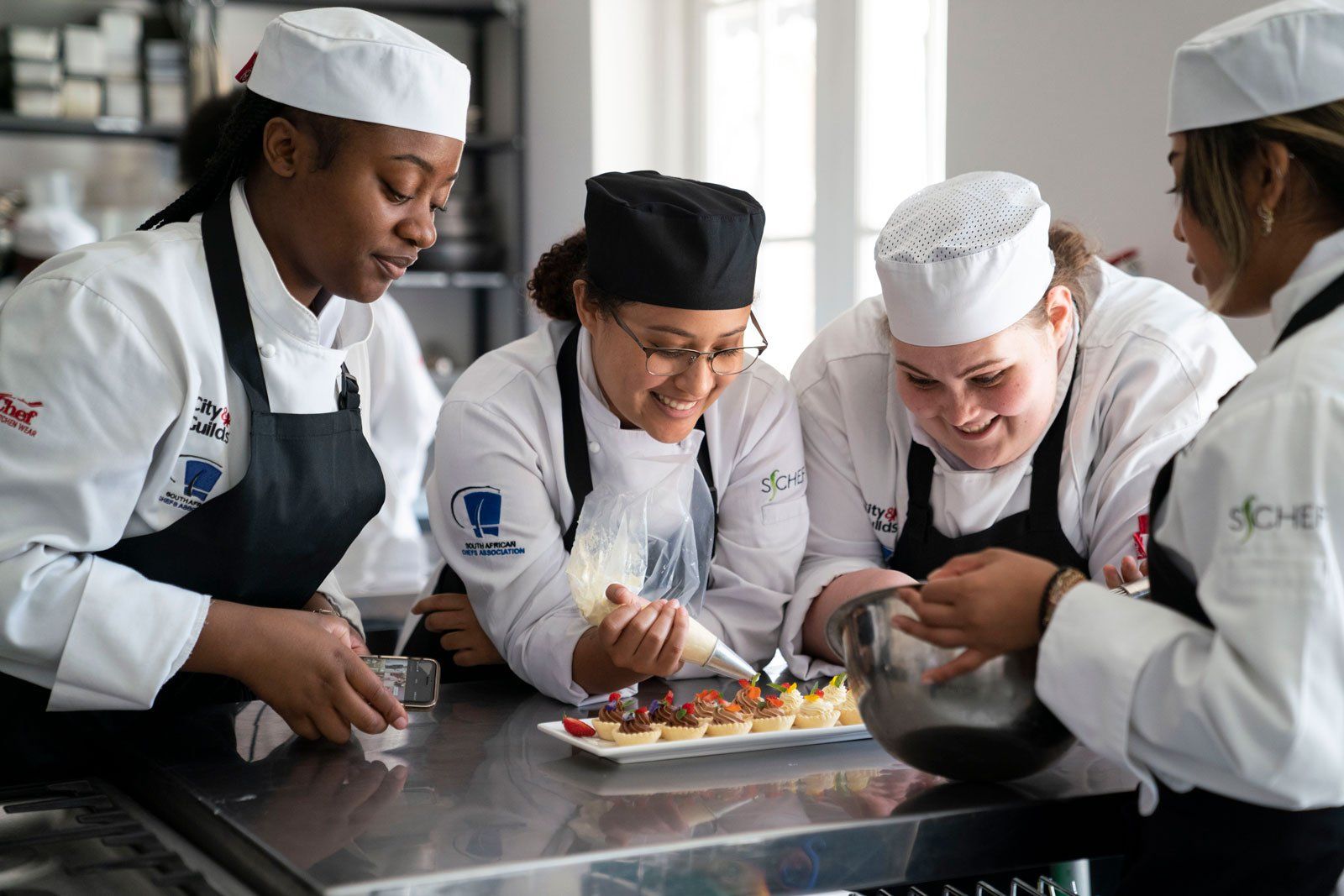 A group of female chefs are preparing food in a kitchen.