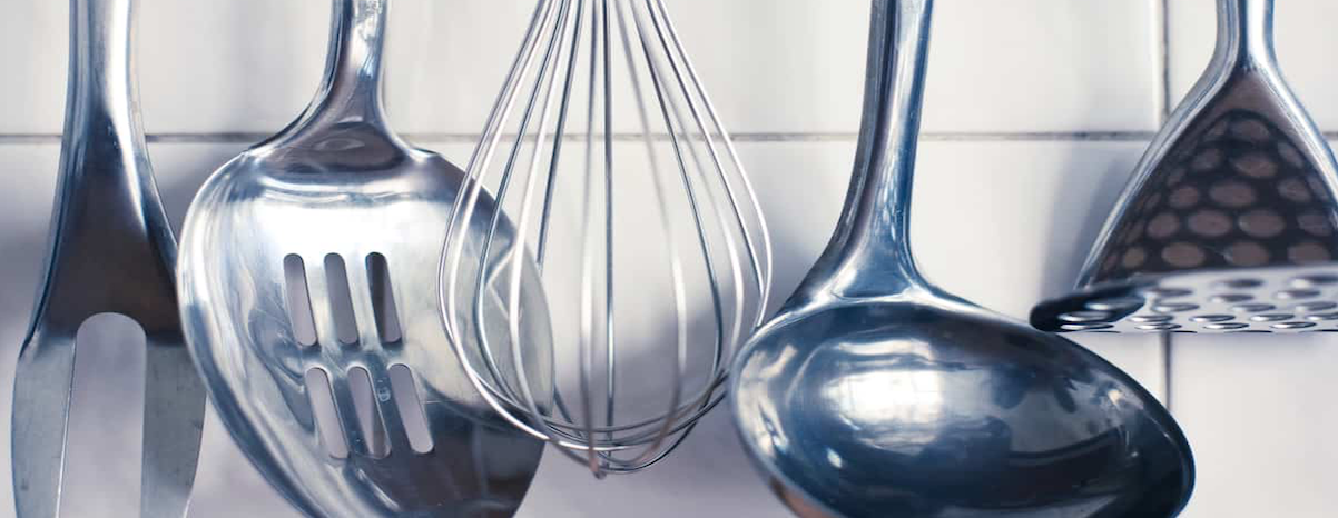 A bunch of kitchen utensils are hanging on a wall.
