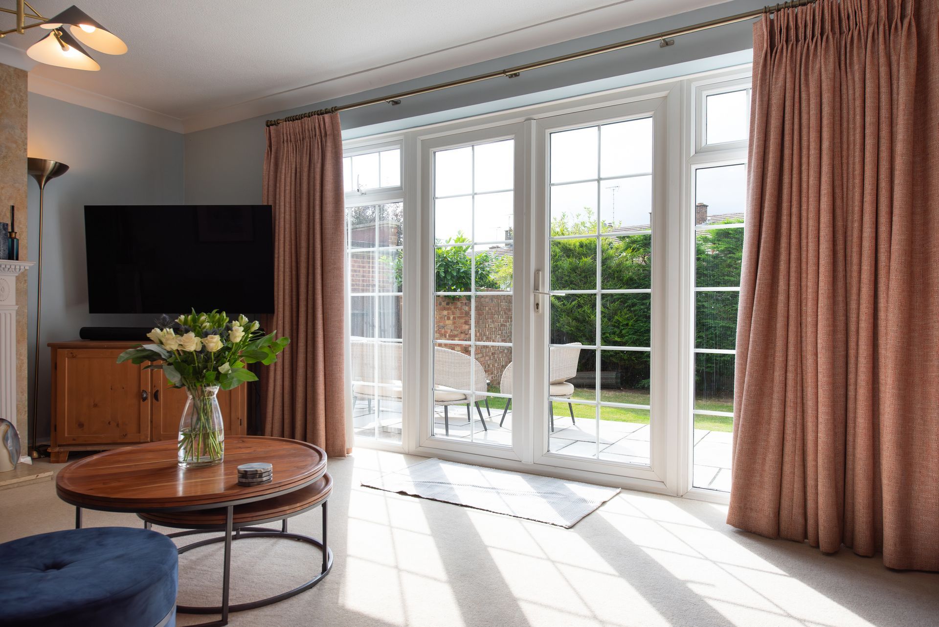 A living room with a table , television , and sliding glass doors.