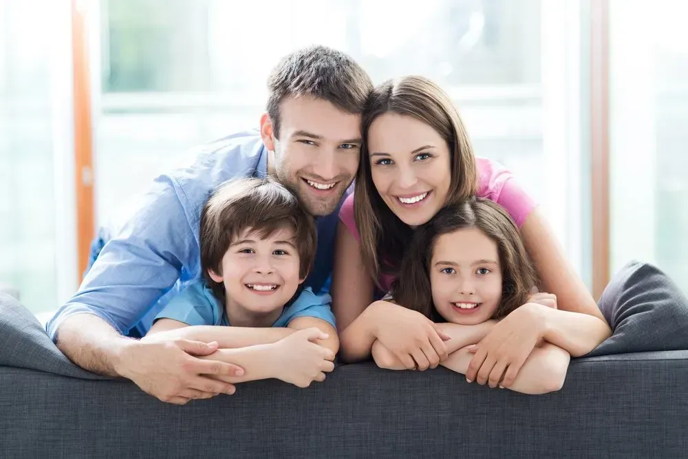 A Family Is Laying on A Couch and Smiling for The Camera — Health Hub Mackay in Bowen, QLD