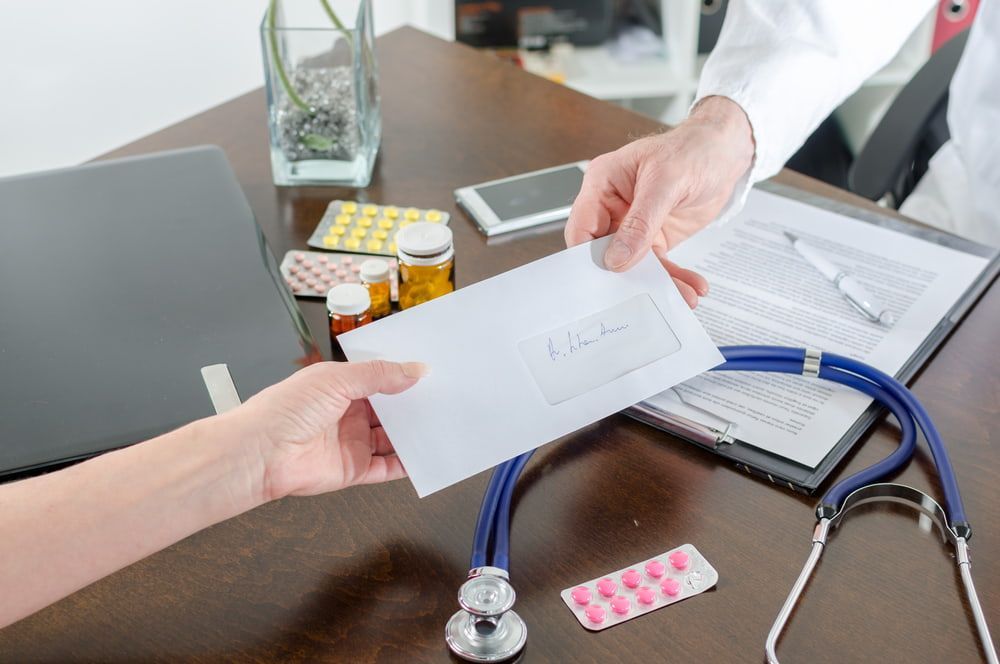 A Doctor Is Handing An Envelope To A Patient — Health Hub Mackay In Bowen, QLD