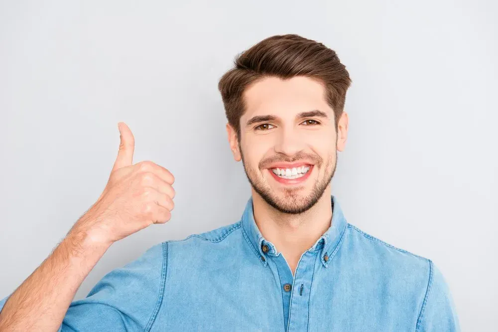 A Man in A Blue Shirt Is Smiling and Giving a Thumbs Up — Health Hub Mackay in Mackay, QLD