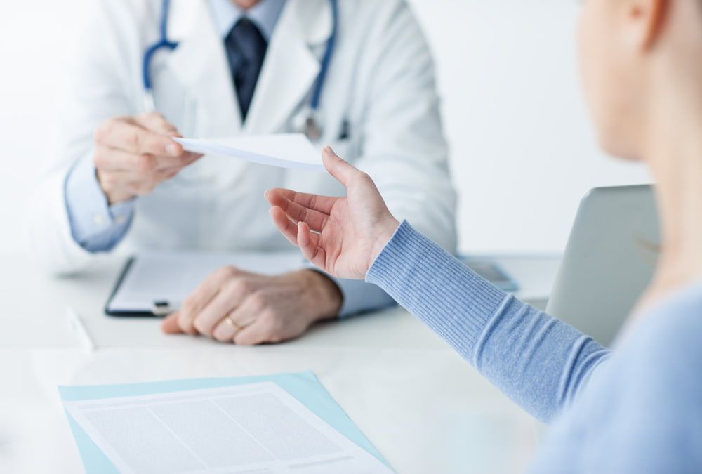 A Doctor Is Talking To A Patient While Holding A Piece Of Paper — Health Hub Mackay In Airlie Beach, QLD