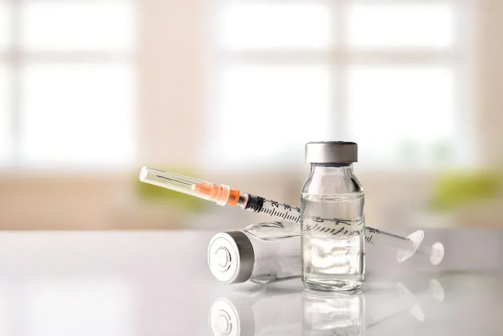 A Syringe Is Sitting Next to A Bottle of Vaccine on A Table — Health Hub Mackay in Mackay, QLD