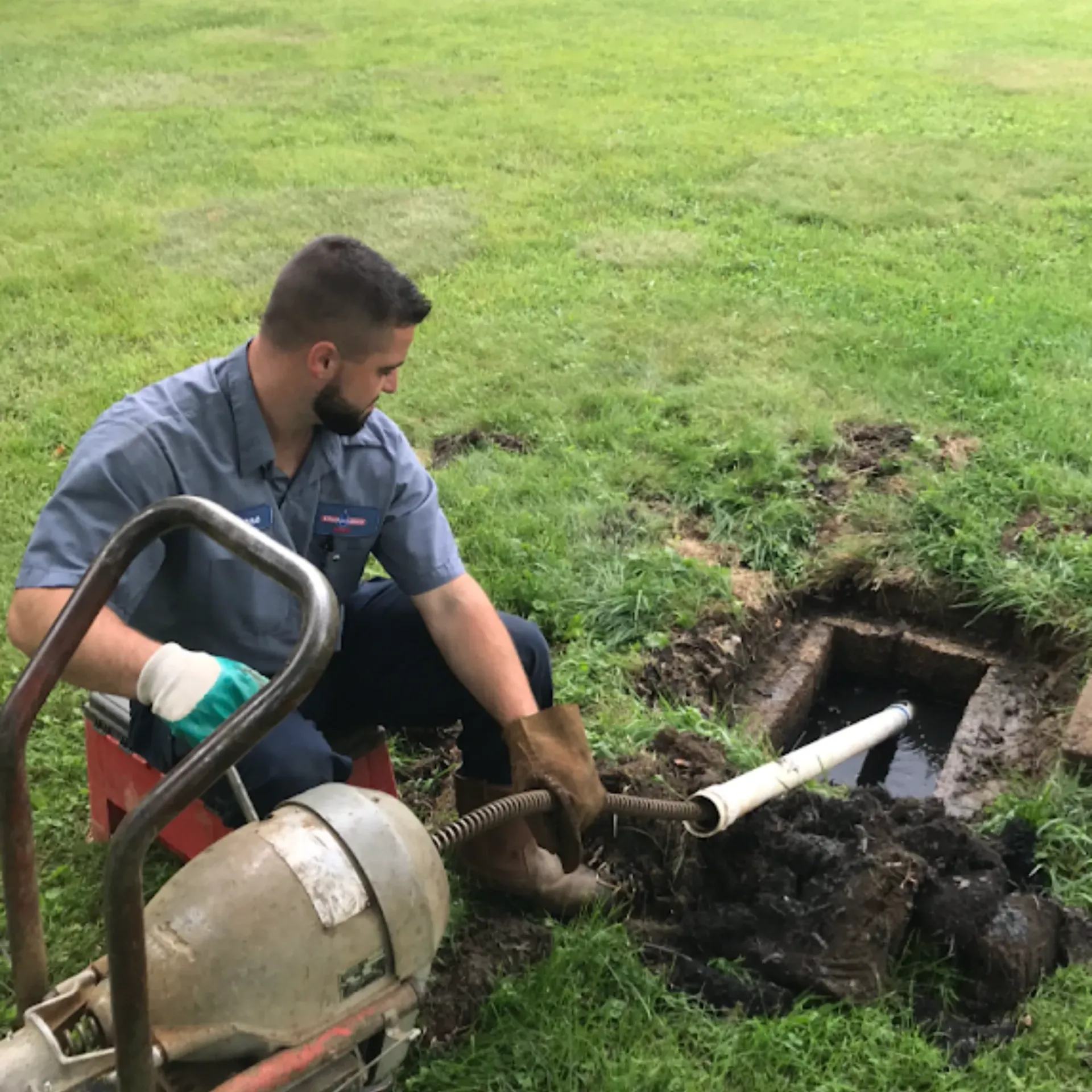 Affordable Waste Services - A man is working on a drain in the grass