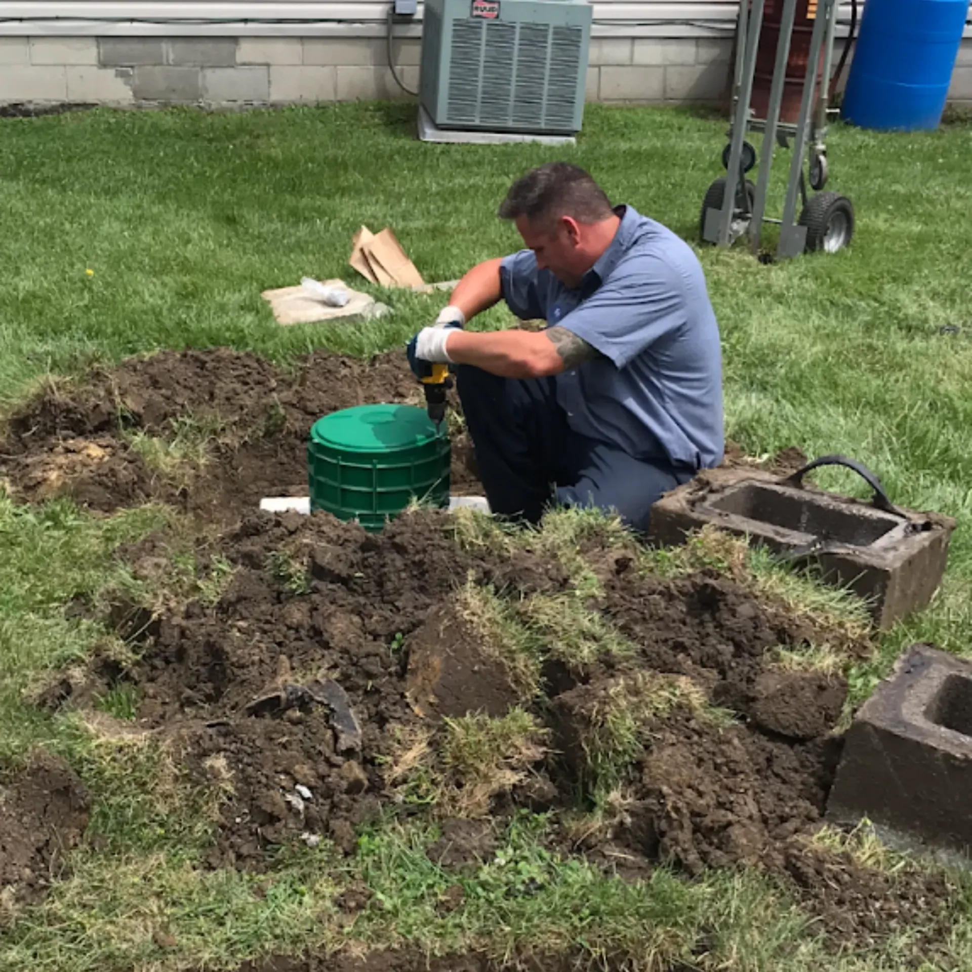Affordable Waste Services - A man is kneeling in the dirt in front of a green bucket