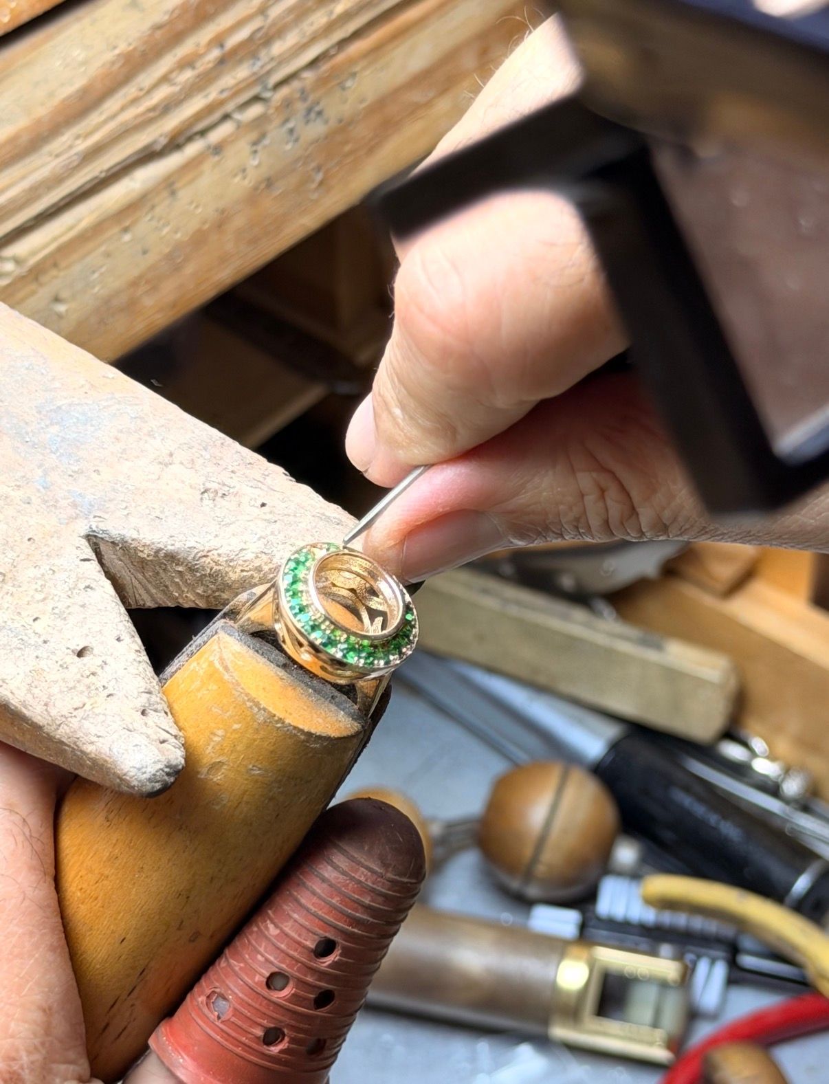 Jeweler using a rotary tool to polish a diamond ring, close-up on hands and ring.