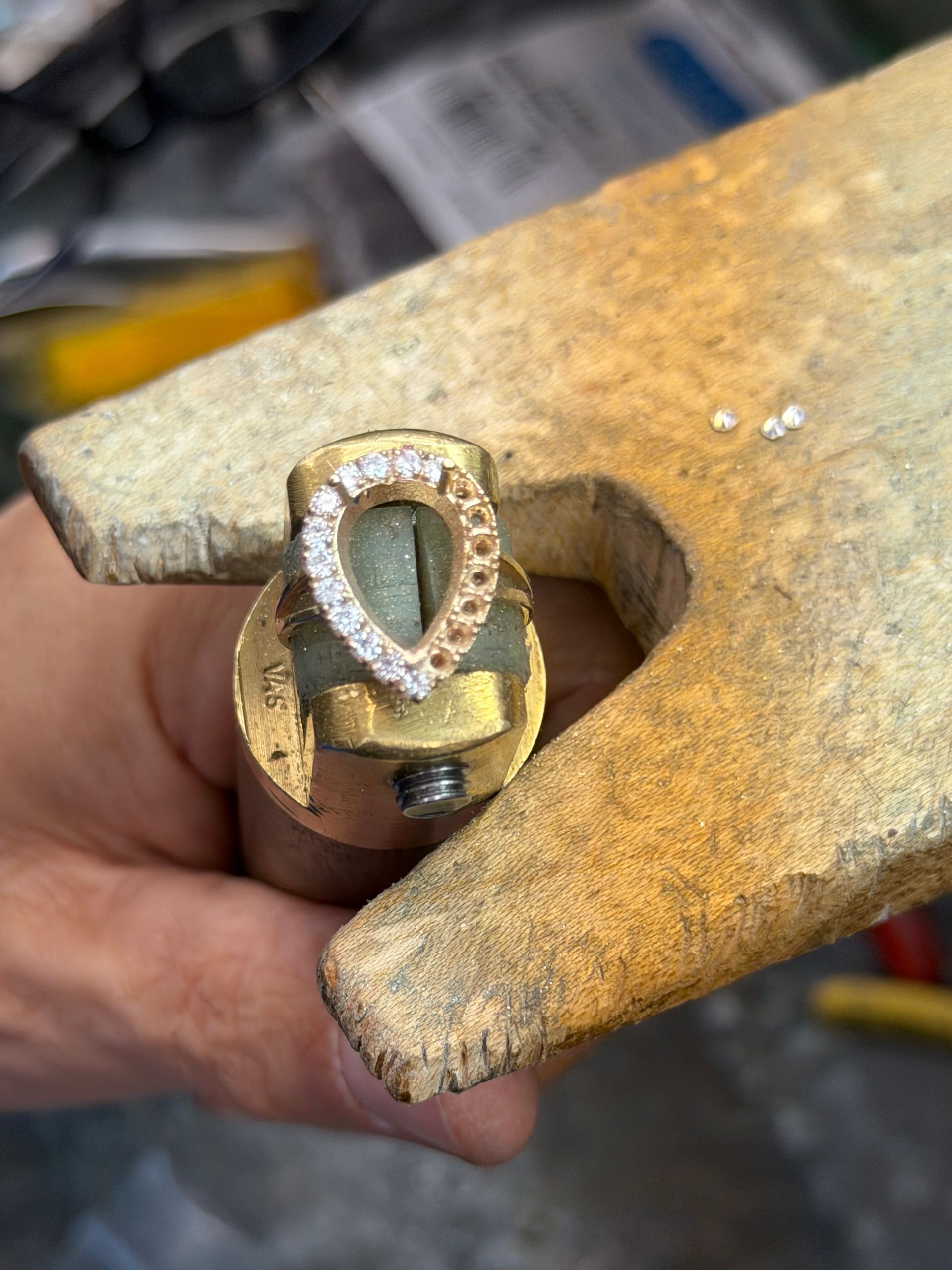 Jeweler's hands holding a diamond ring with tweezers, setting a stone.