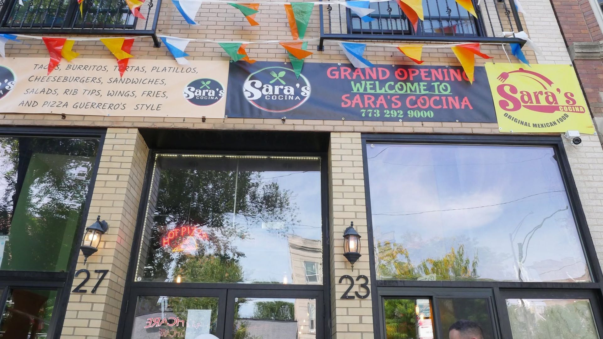 Storefront with colorful “Sara’s Cocina” signs above glass doors and windows.