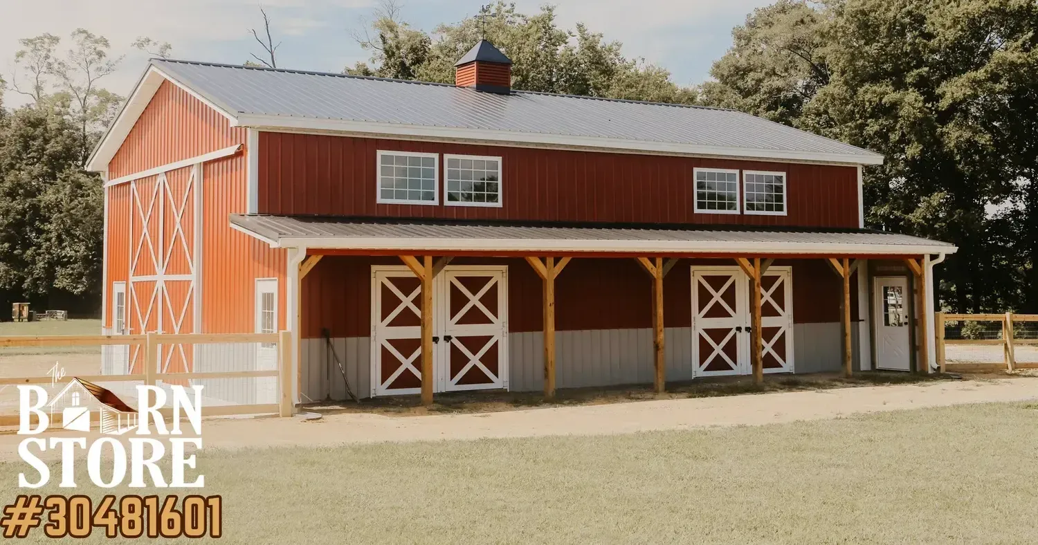 A large red barn with white trim and multiple doors, surrounded by a fenced yard and lush greenery.
