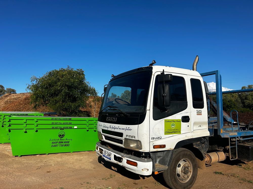 A White Truck is Parked in Front of a Green Dumpster  — Leichhardt River Nursery & Skip Bin Hire In Kalkadoon, QLD