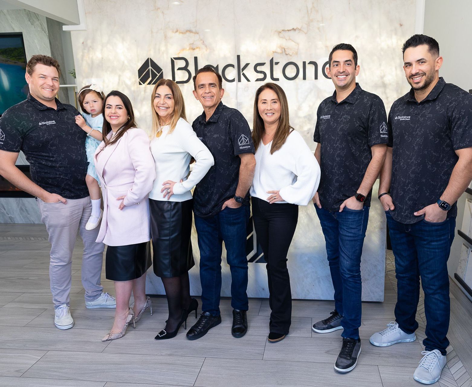 A group of people are posing for a picture in front of a sign that says Blackstone, serving San Diego.