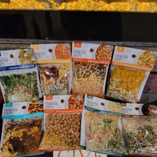 A bunch of bags of food are sitting on top of each other on a table.