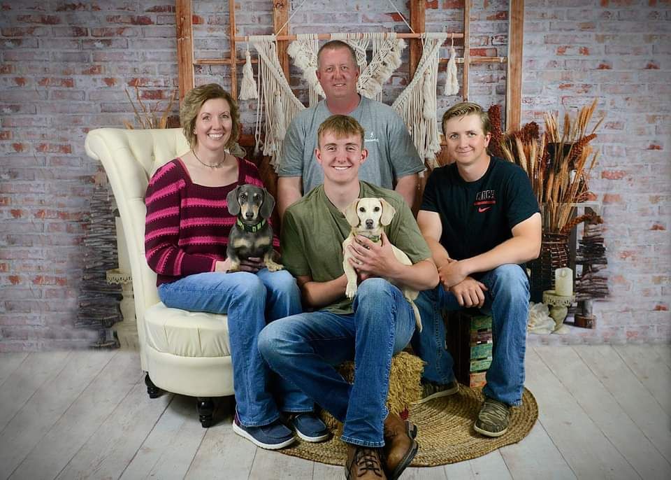 A family is posing for a picture with their dog.
