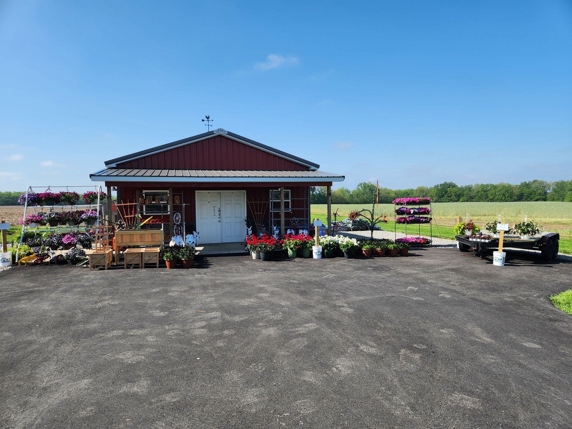 A red barn with a lot of potted plants in front of it.