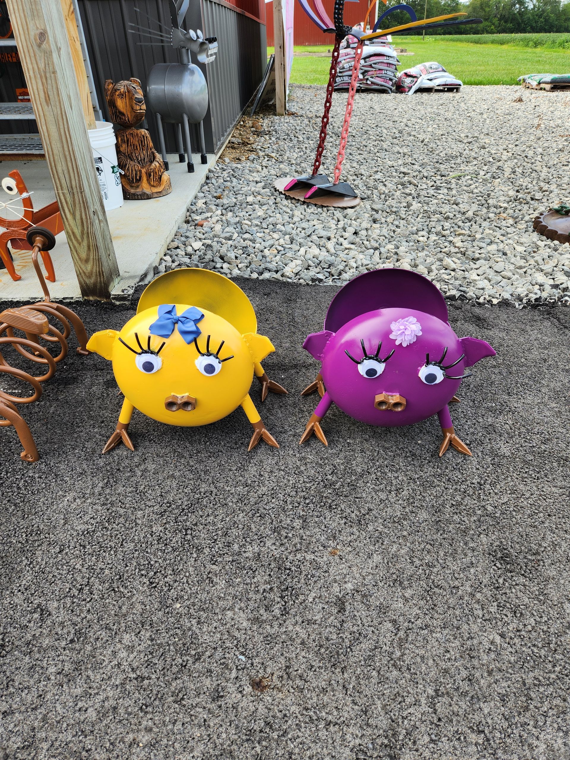 A yellow and purple frog are sitting next to each other on the ground.