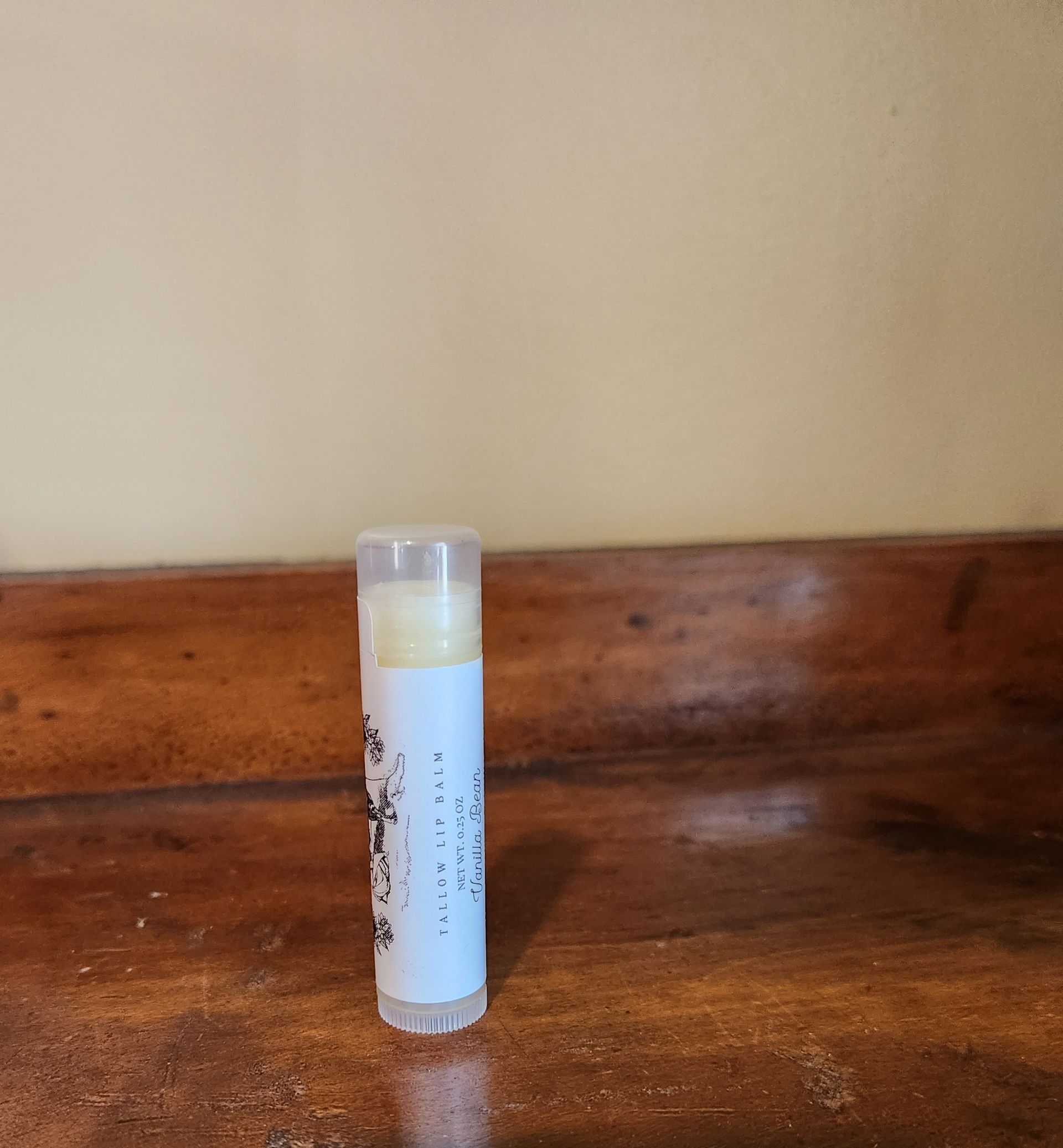 A tube of lip balm is sitting on a wooden table.