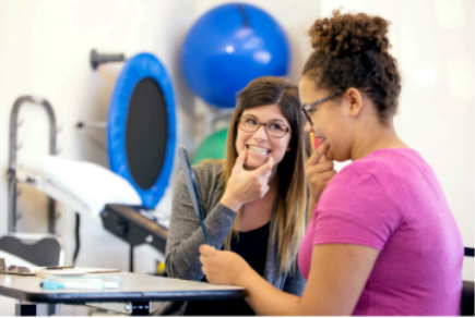 Two women are sitting at a table talking to each other.