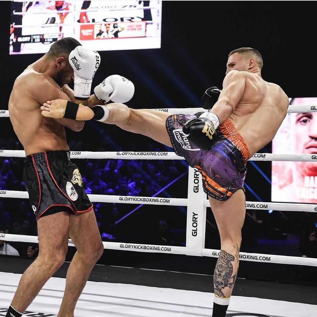 Kickboxers in a ring; one throws a kick, other defends.