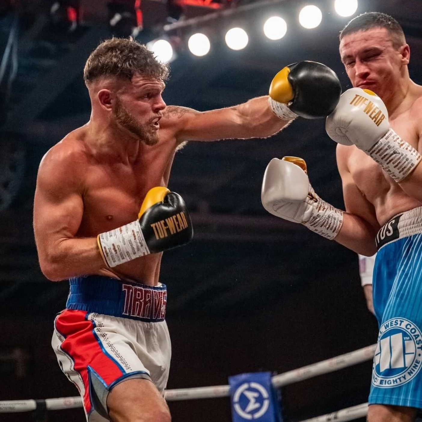 Boxer throwing a punch in a boxing ring, the other boxer defending.