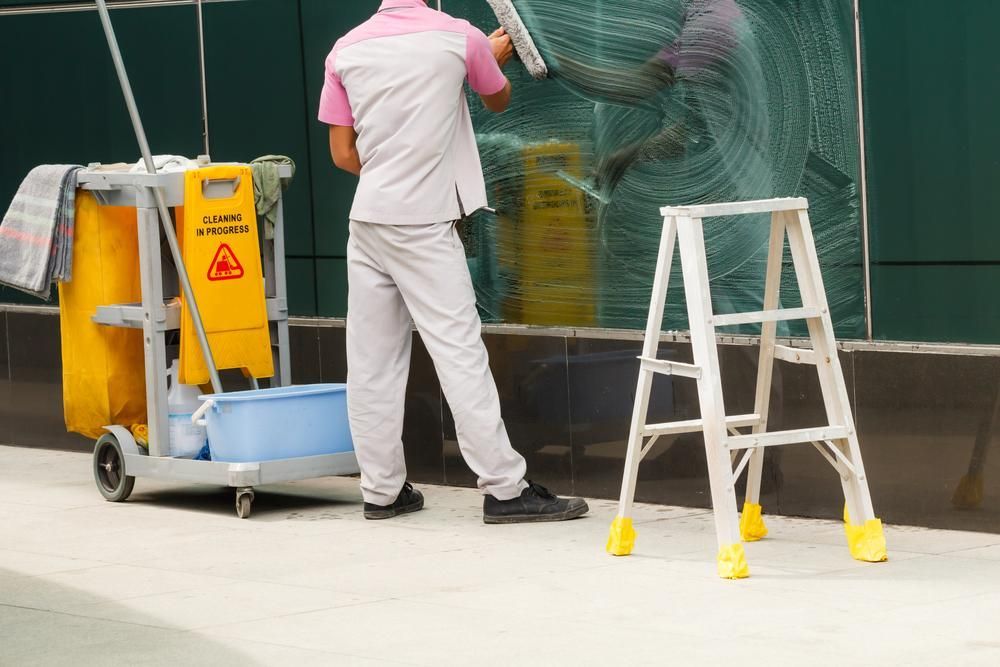 A Man Is Cleaning a Window with A Mop — KJ's Elite Cleaning Services Newcastle in Beresfield, NSW