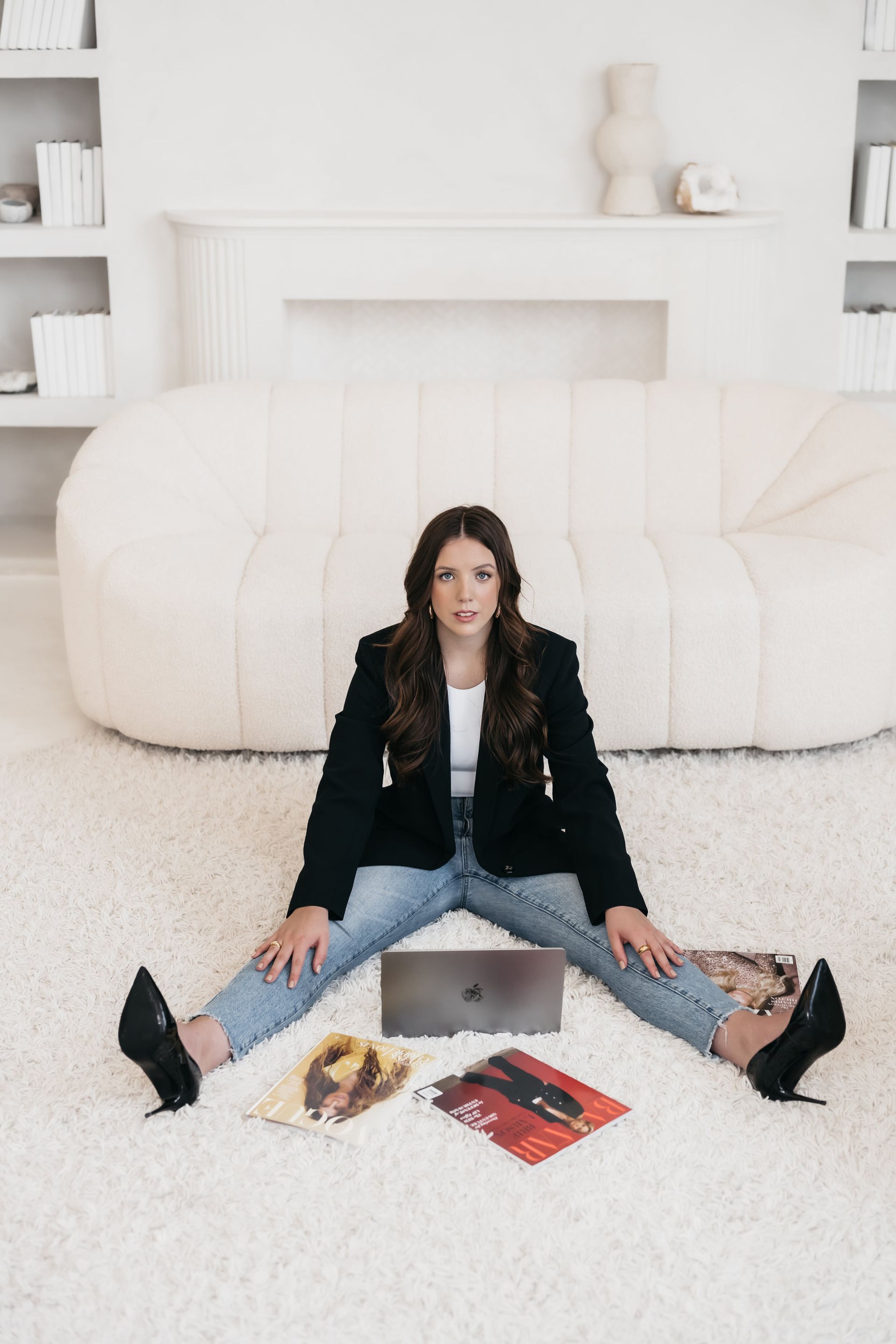 A woman is sitting on the floor with her legs crossed in front of a couch.