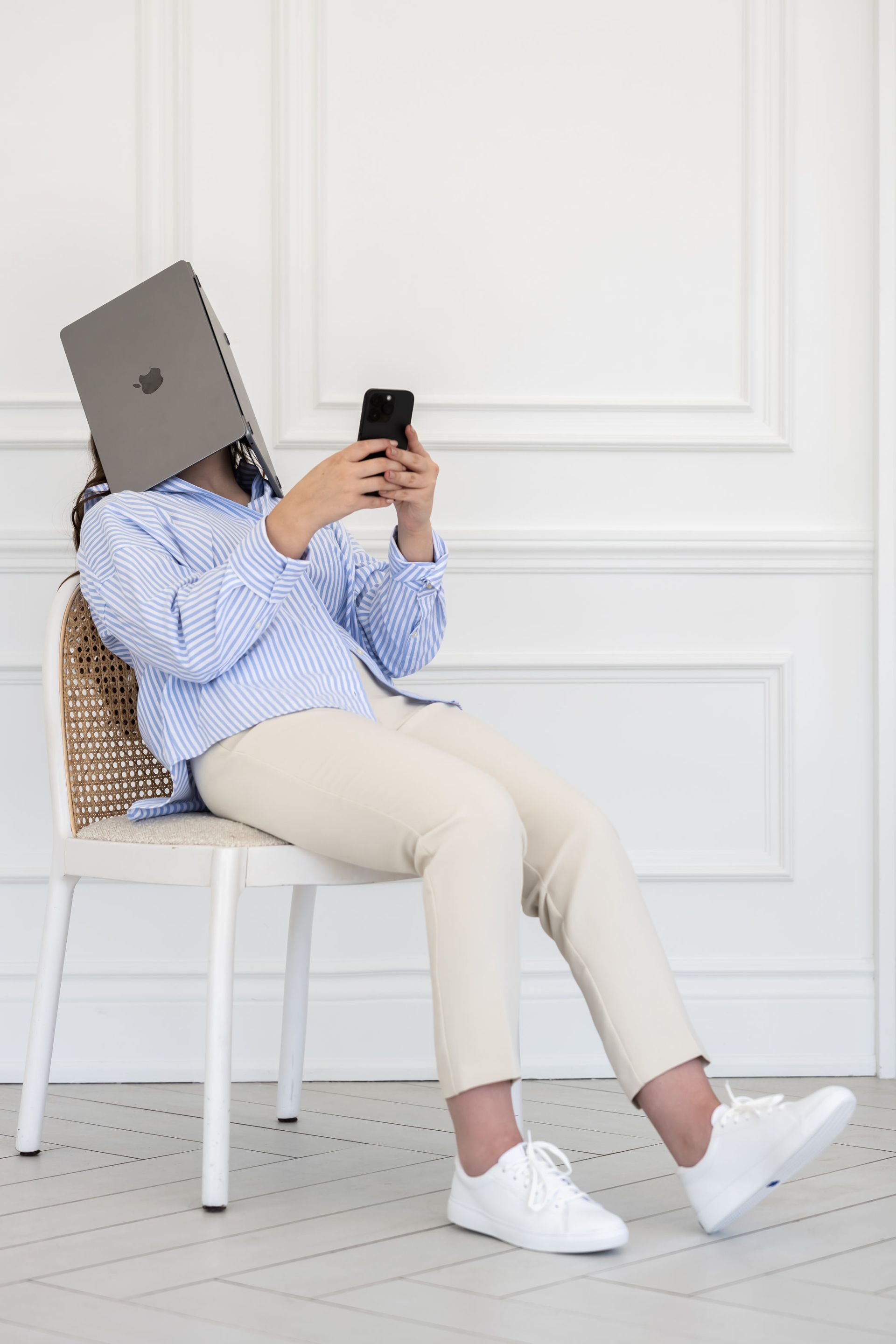 A woman is sitting in a chair with a laptop on her head.