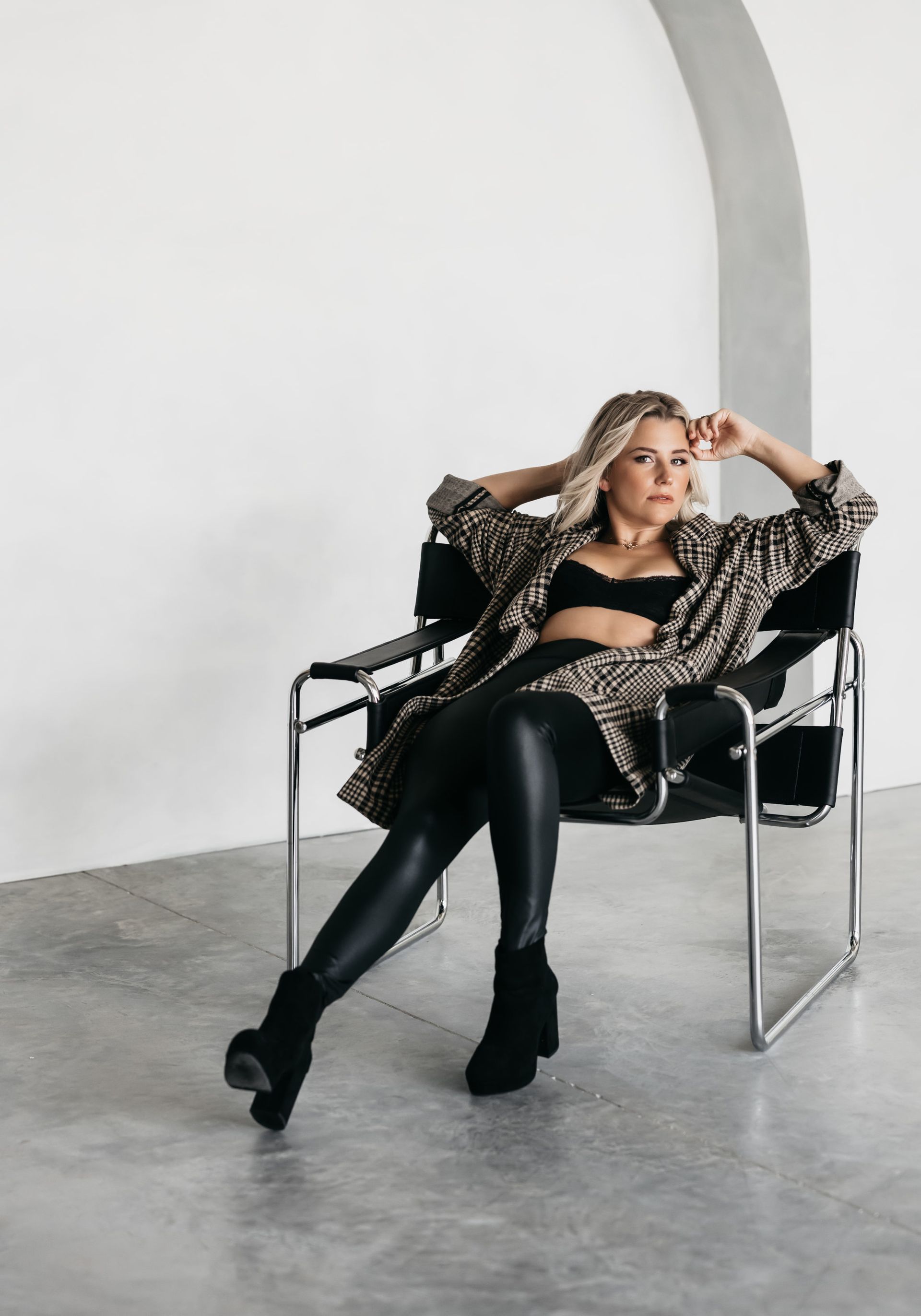 A woman posing for professional headshots in a chair in a room.