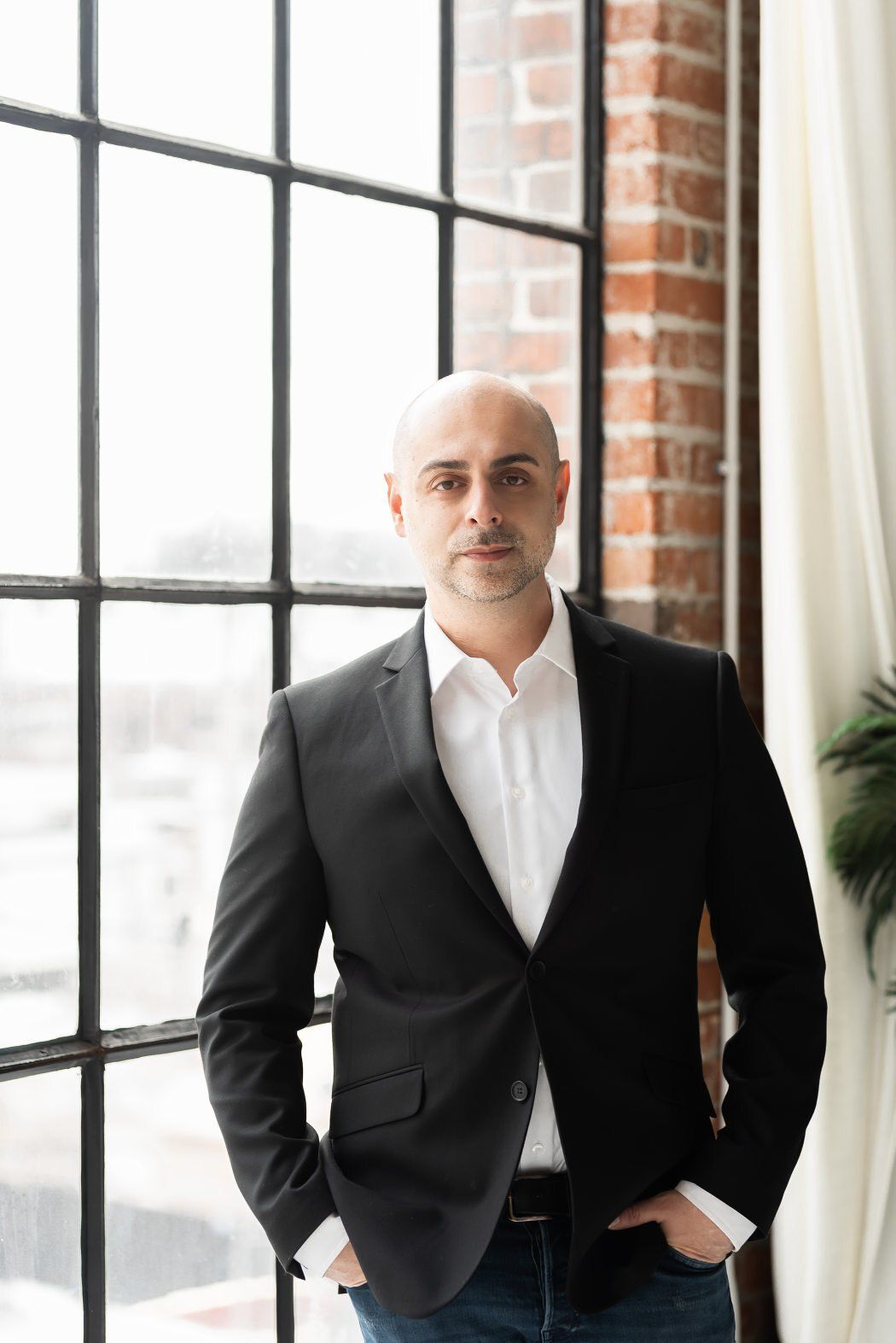 a man with a black and white formal attire standing near the window