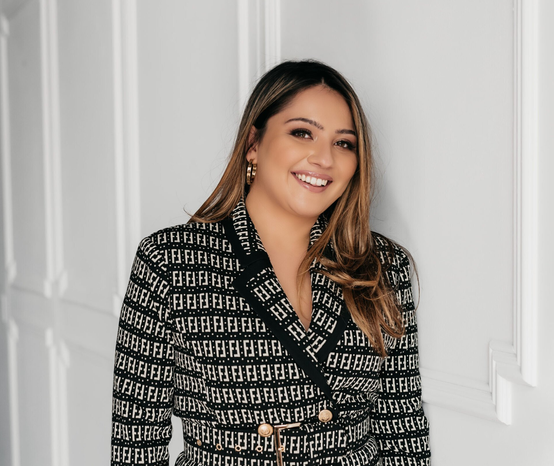 A professional head shot of a woman wearing a patterned black and white suit