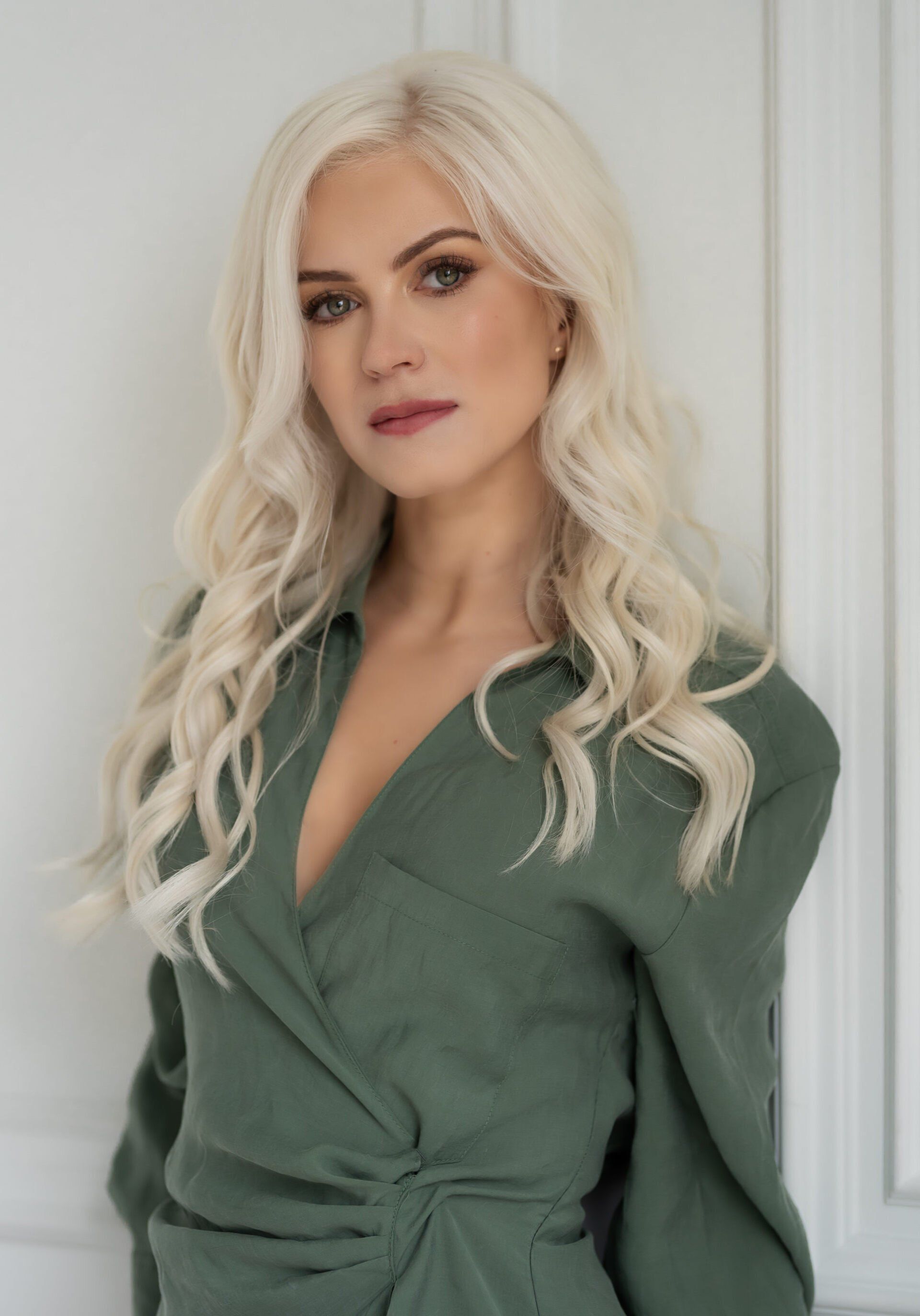 A blonde woman wearing a sage wrap dress