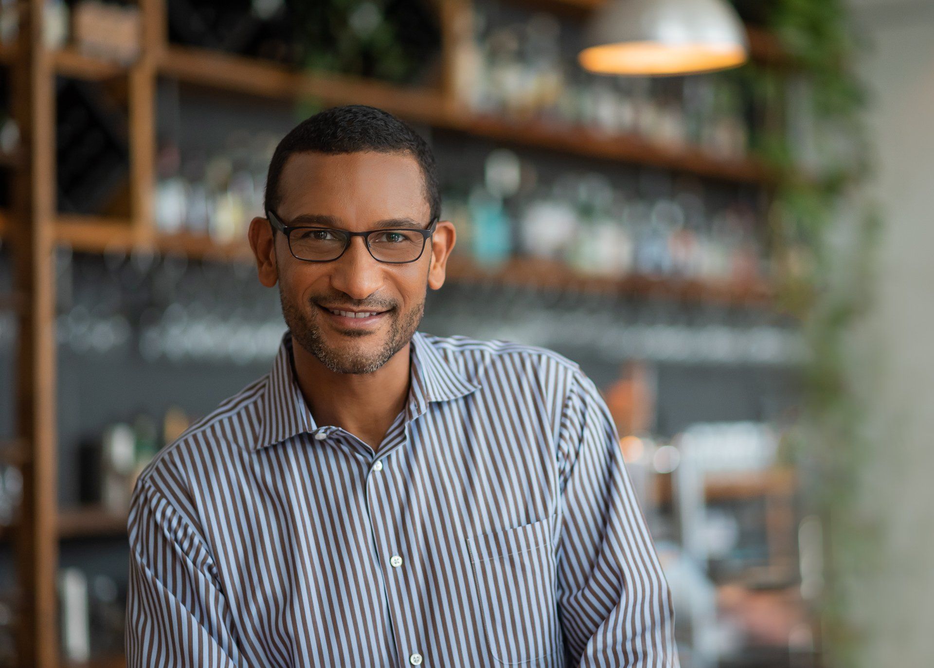 a man in glasses standing in front of a bar.