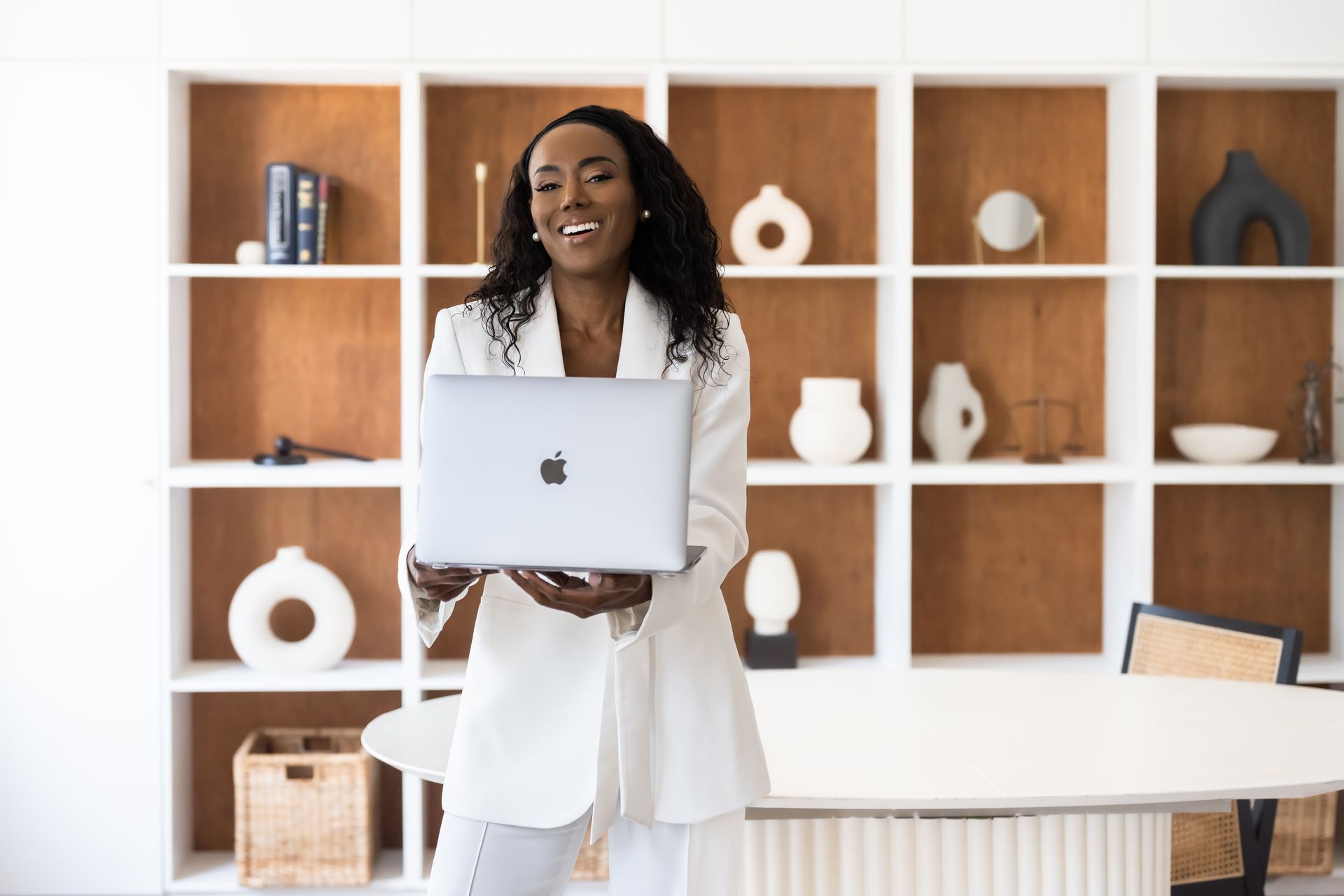 a woman in a white jacket is holding a laptop computer in her hands .