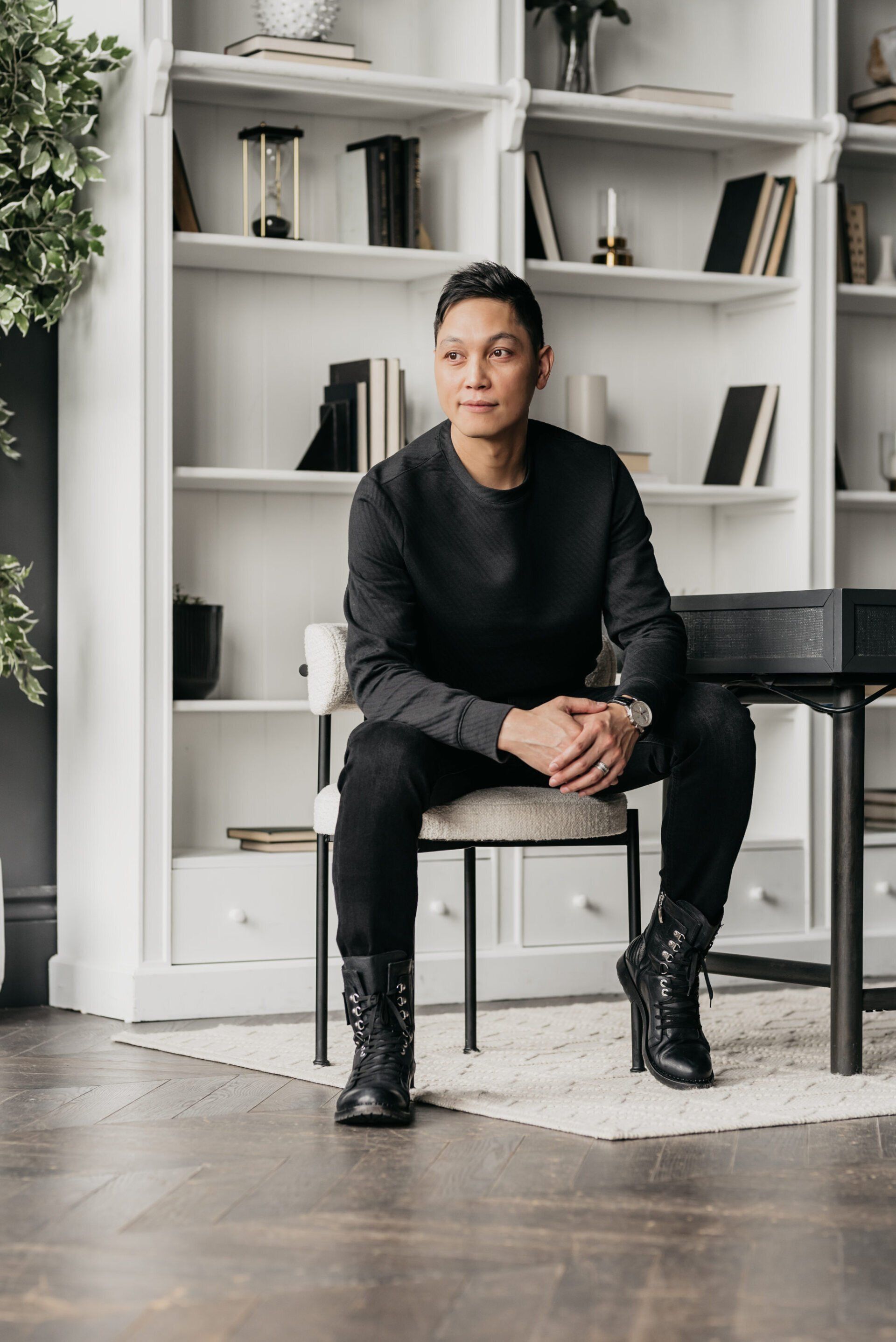 a man sitting on a chair in front of a bookshelf.