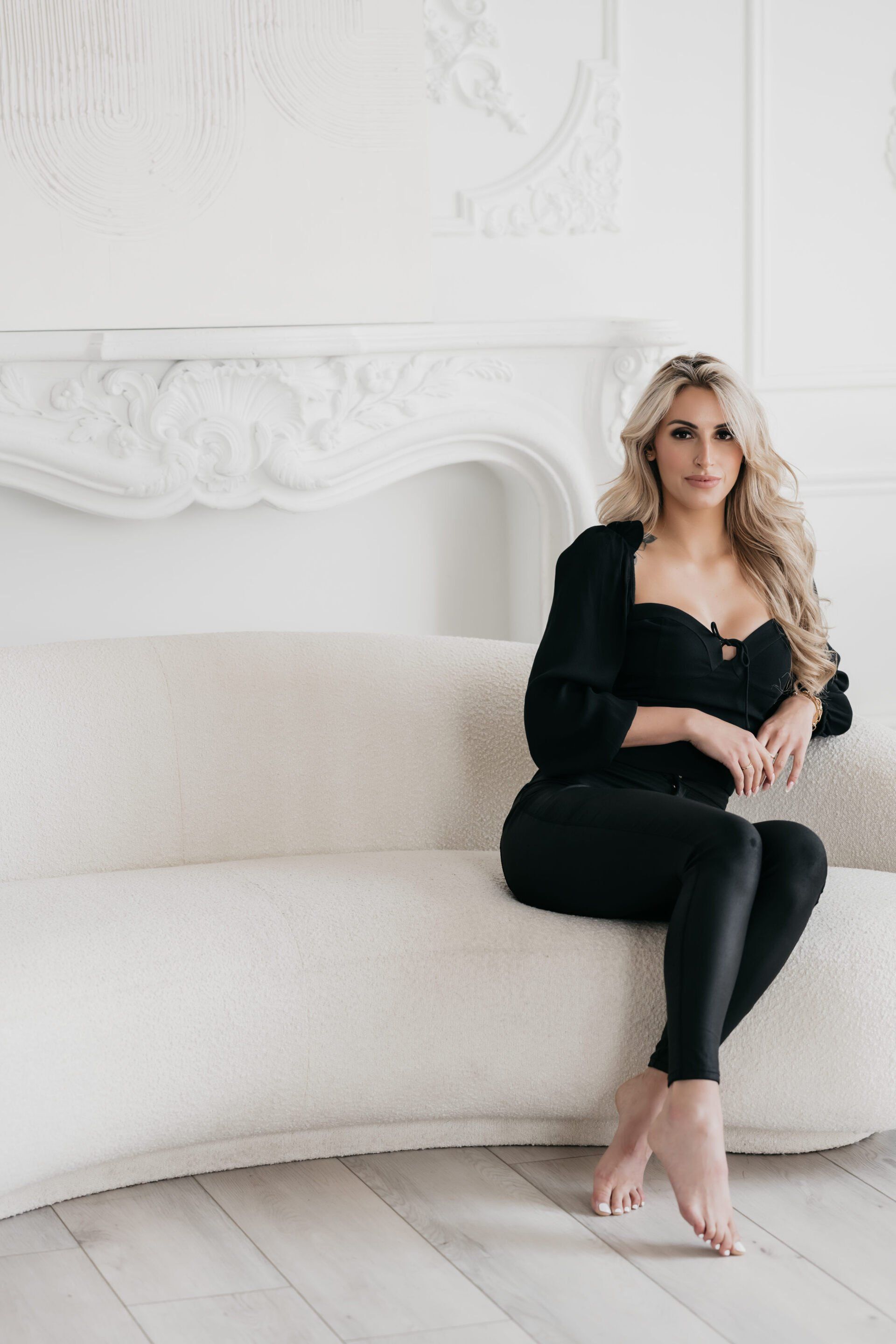 a woman with blonde wavy hair sitting on a white sofa