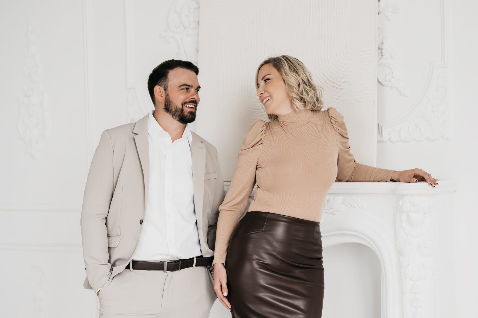 A couple wearing neutral color themed outfits as they look at each other