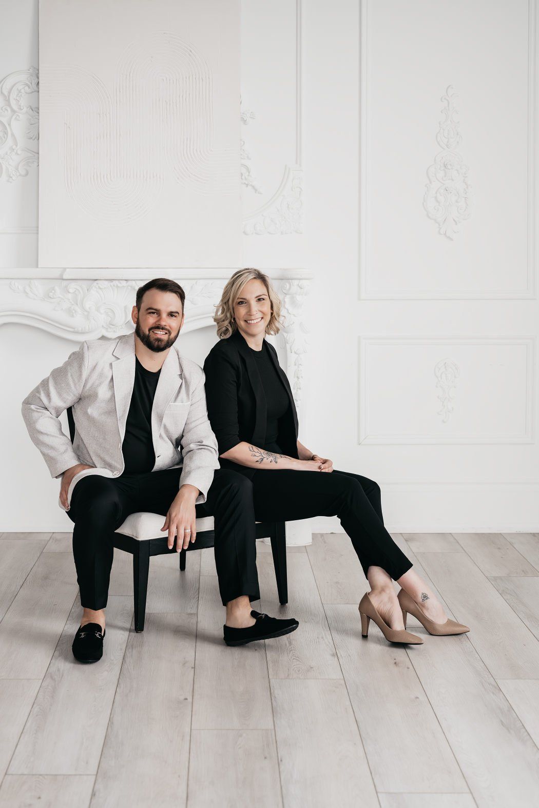 A couple wearing smart casual outfits while sitting on stools