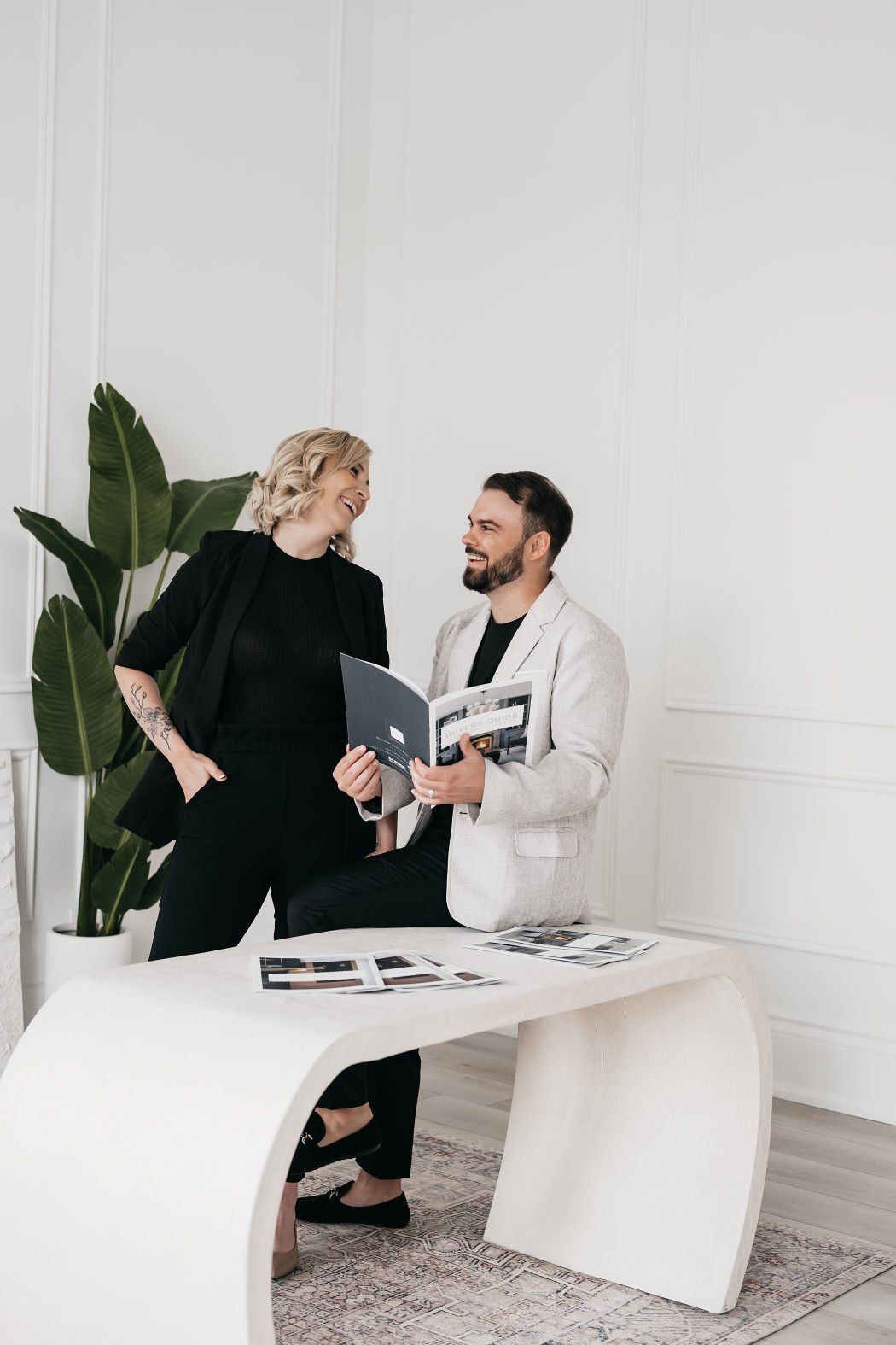 A couple discussing as they stand behind their modern white office desk