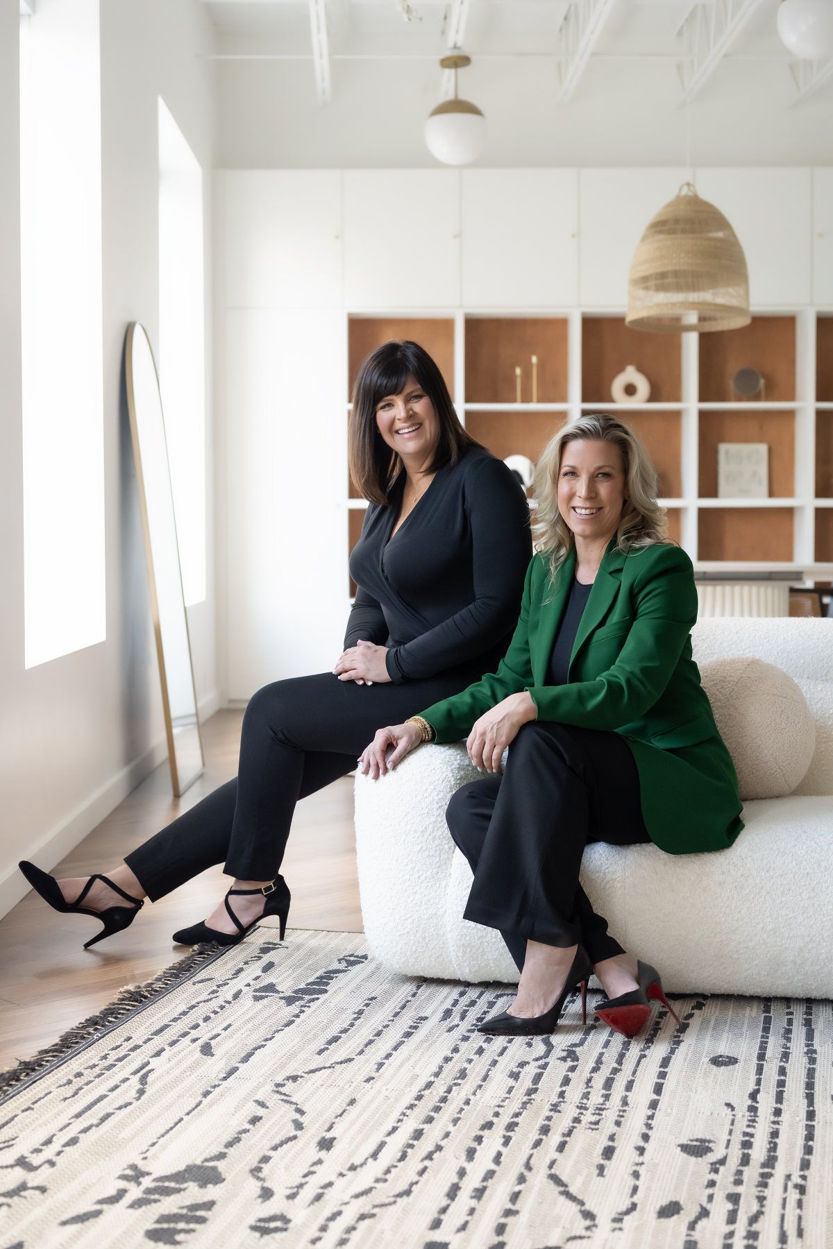Two women are sitting on a couch in a living room.
