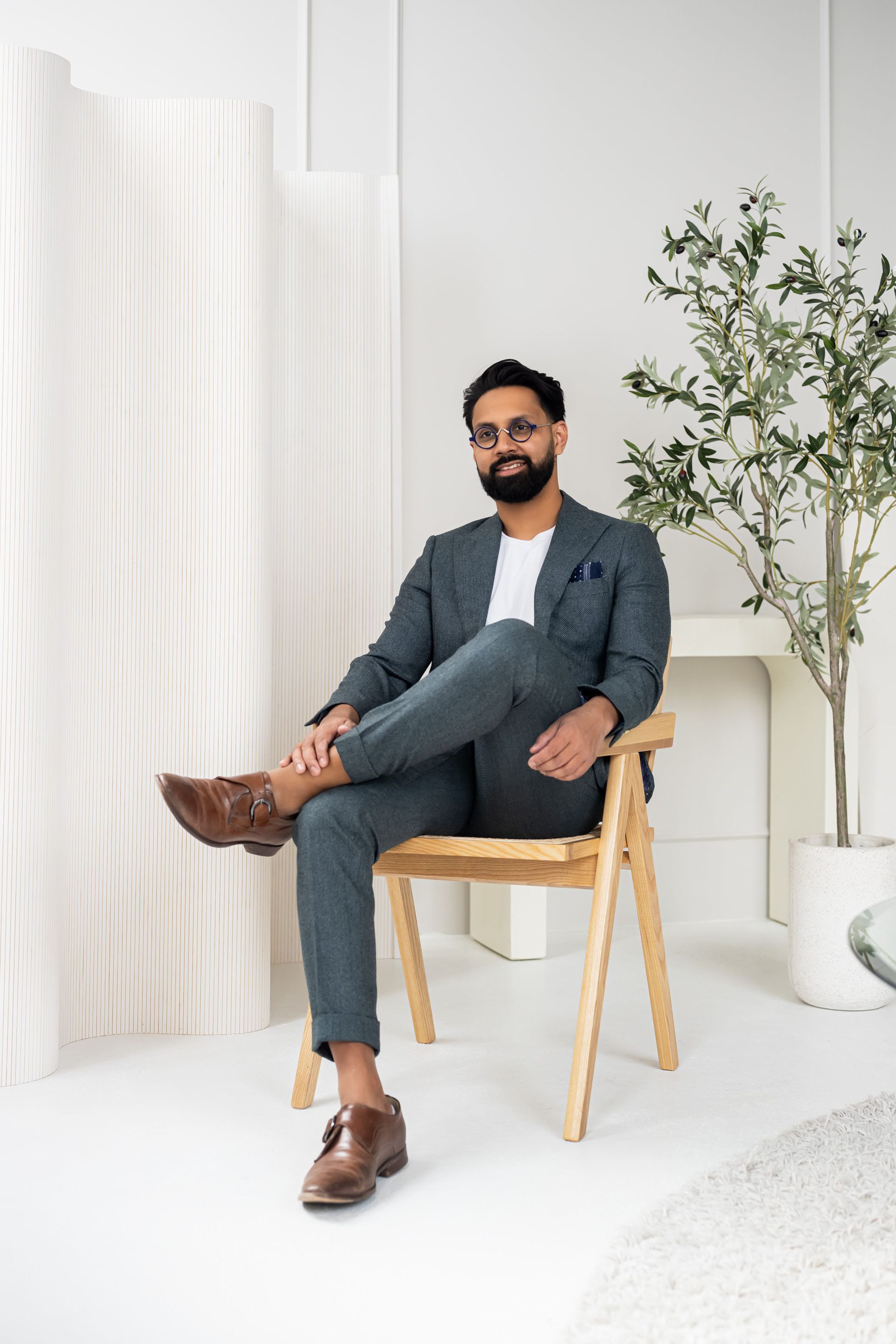 A man in a suit sitting on a chair for executive headshots.