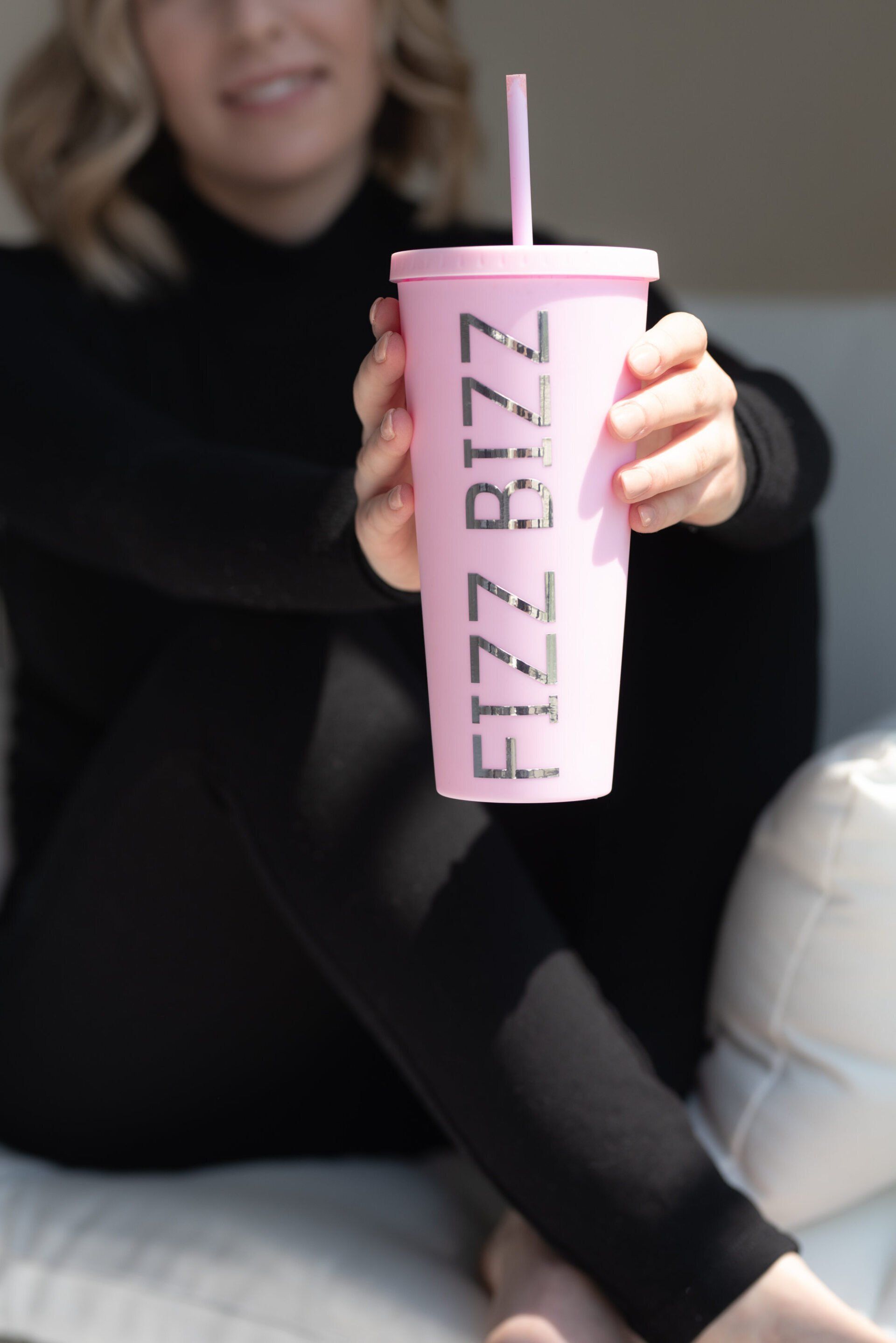 young business owner, sitting with legs crossed and presenting a specialty drink product