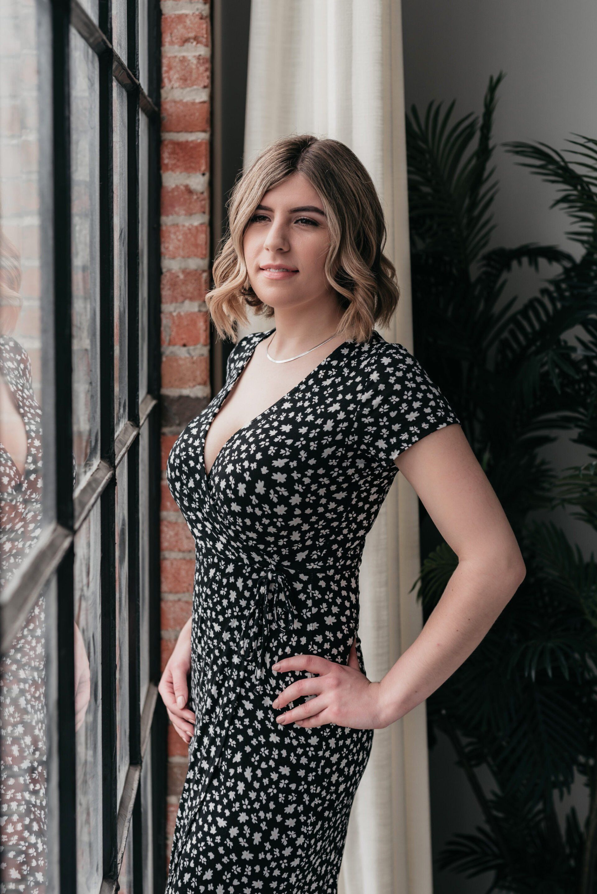 A cheerful female business owner looking out of a large bright window