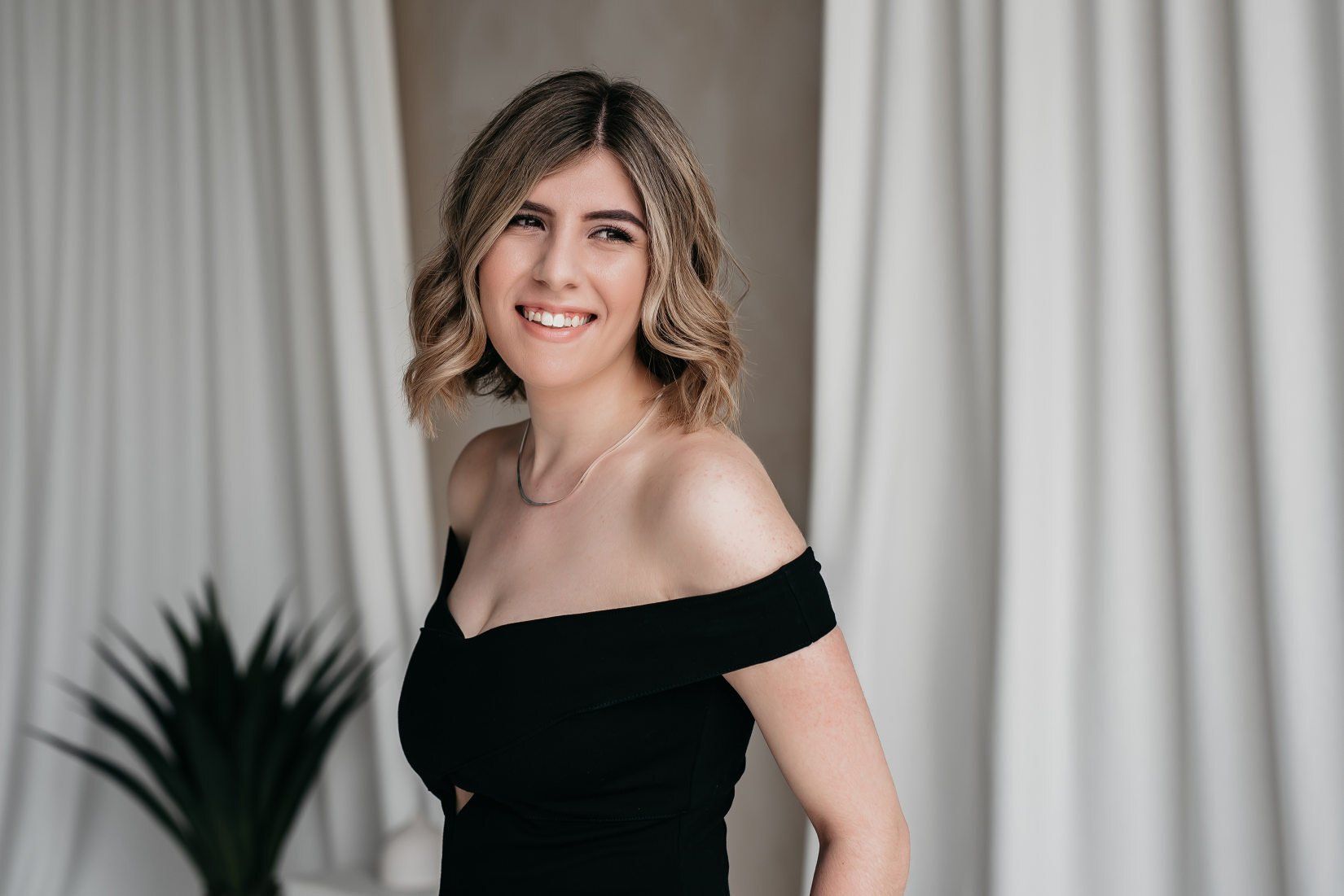 Cheerful, young female business owner wearing a black sleeveless dress