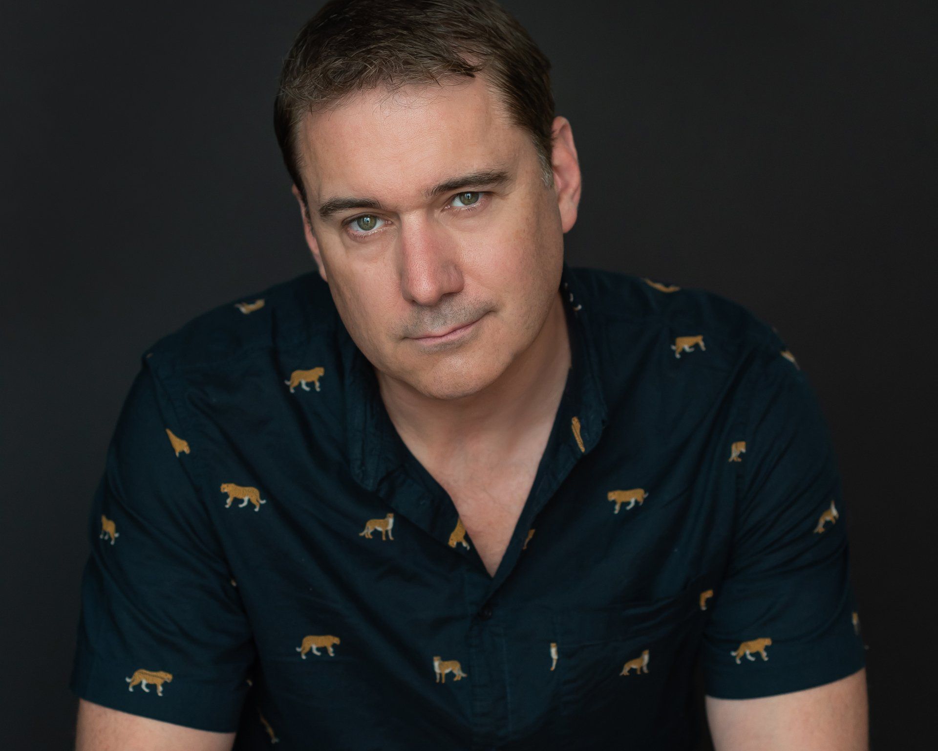 a man wearing a shirt with a tiger on it looking at the canera