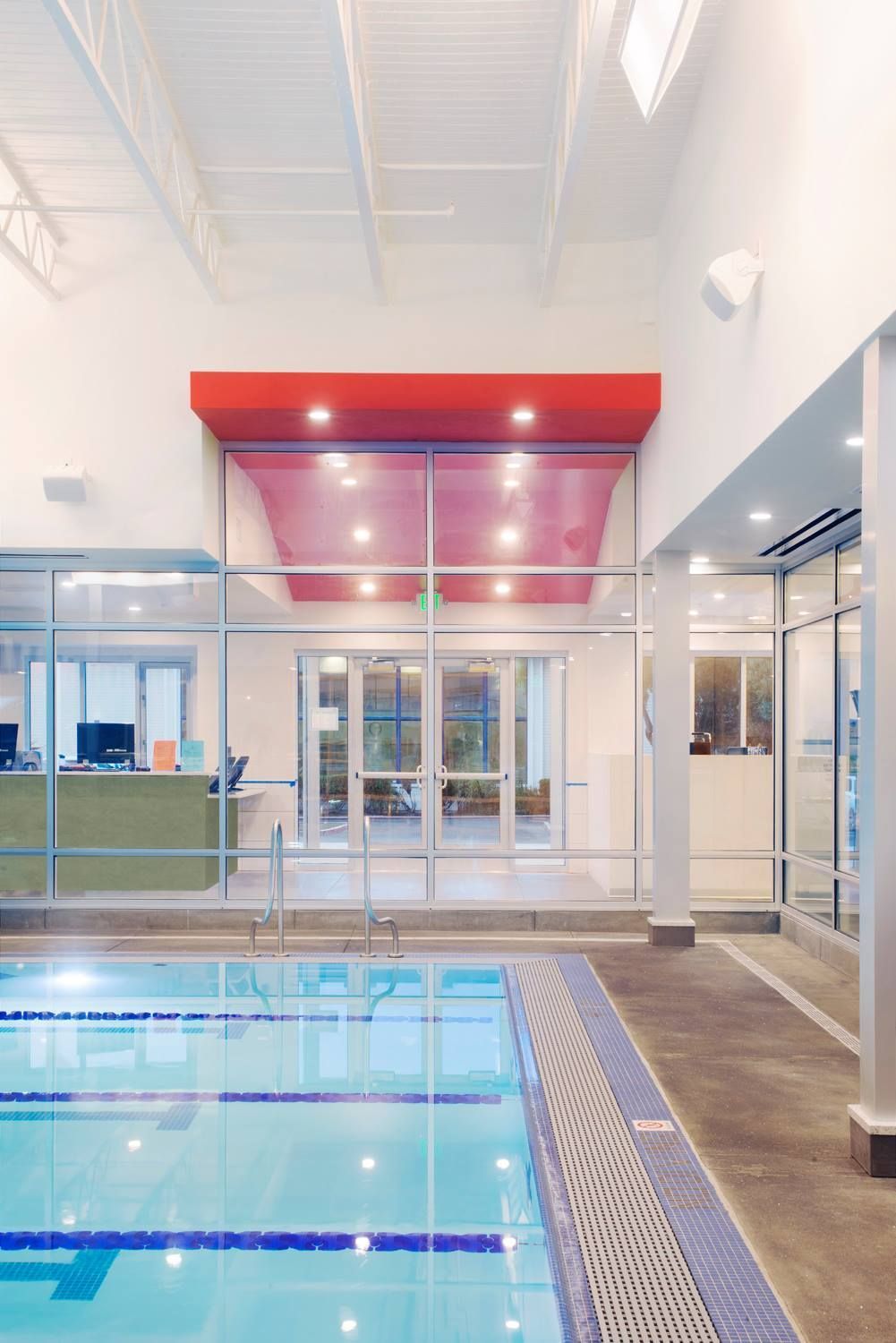 Indoor swimming pool with glass doors and a red awning in the background