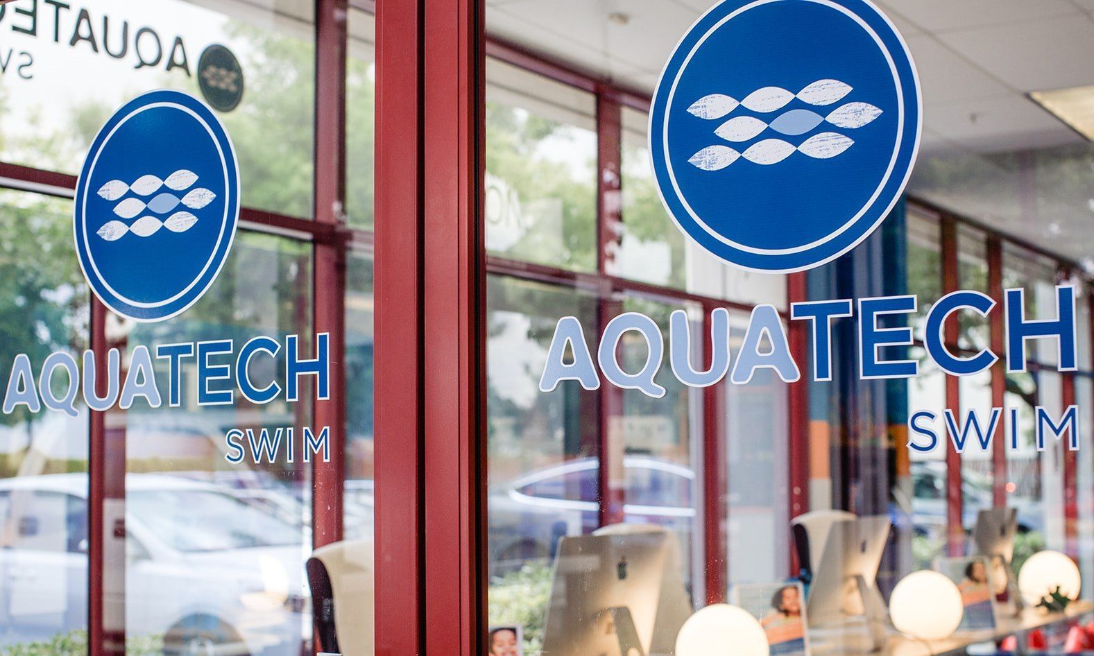 Aquatech Swim storefront window with blue circular logo and white lettering