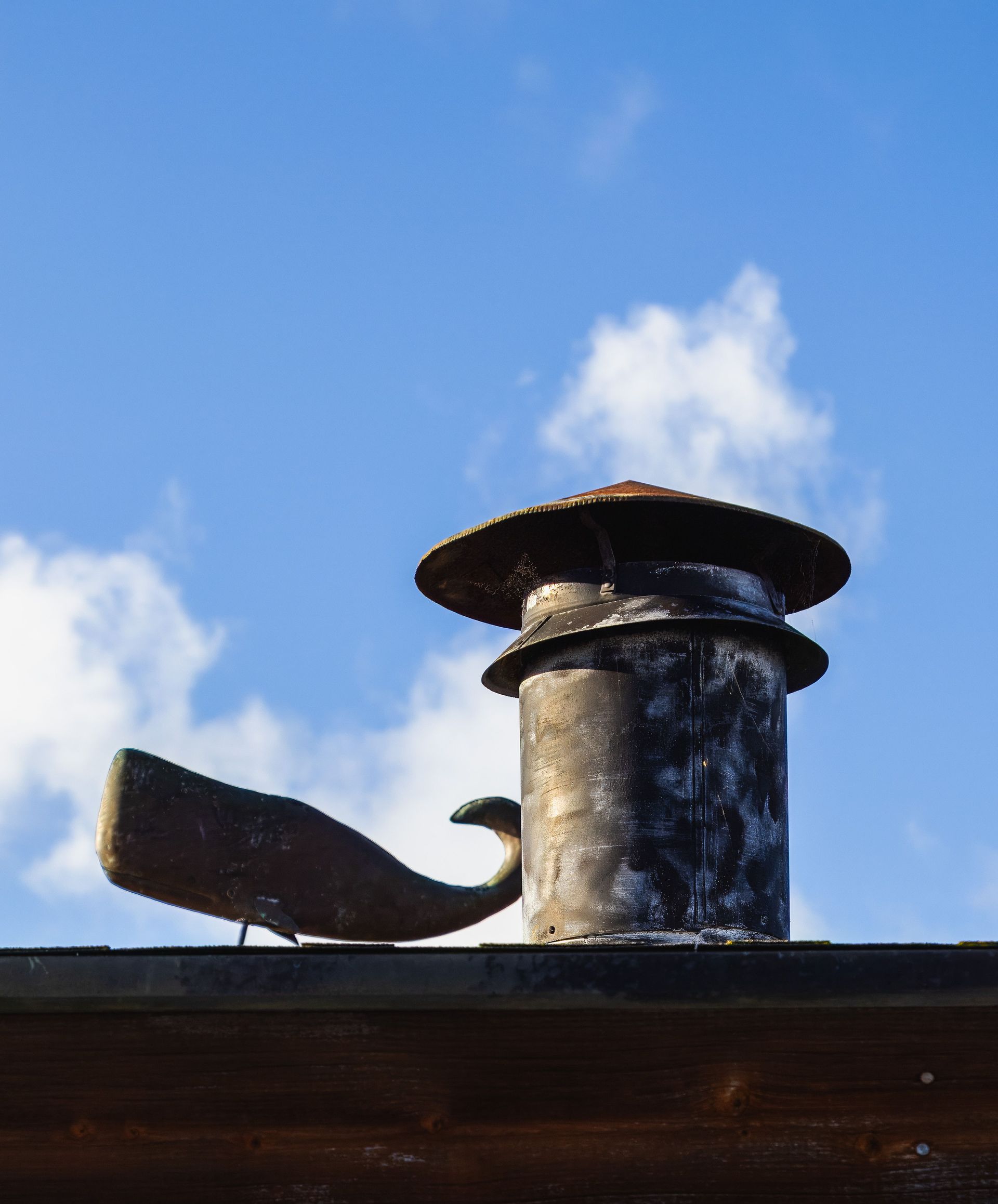 Metal chimney vent on a rooftop against a blue sky
