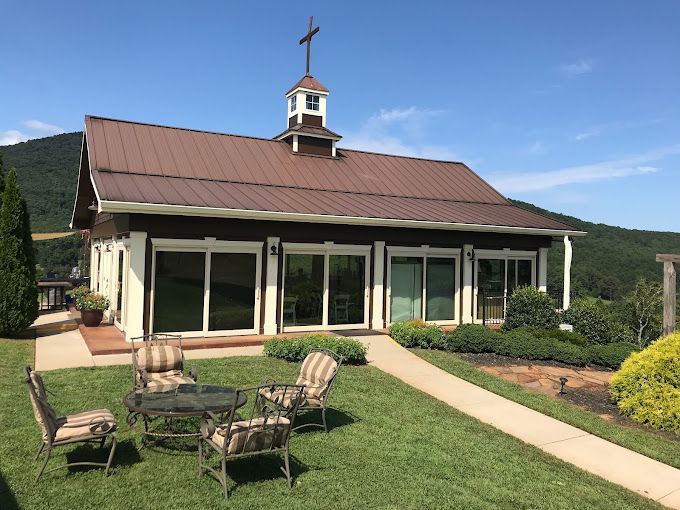 There is a table and chairs in the grass in front of a house.