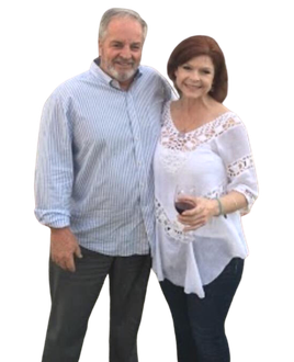 A man and a woman are posing for a picture and the woman is holding a glass of wine.